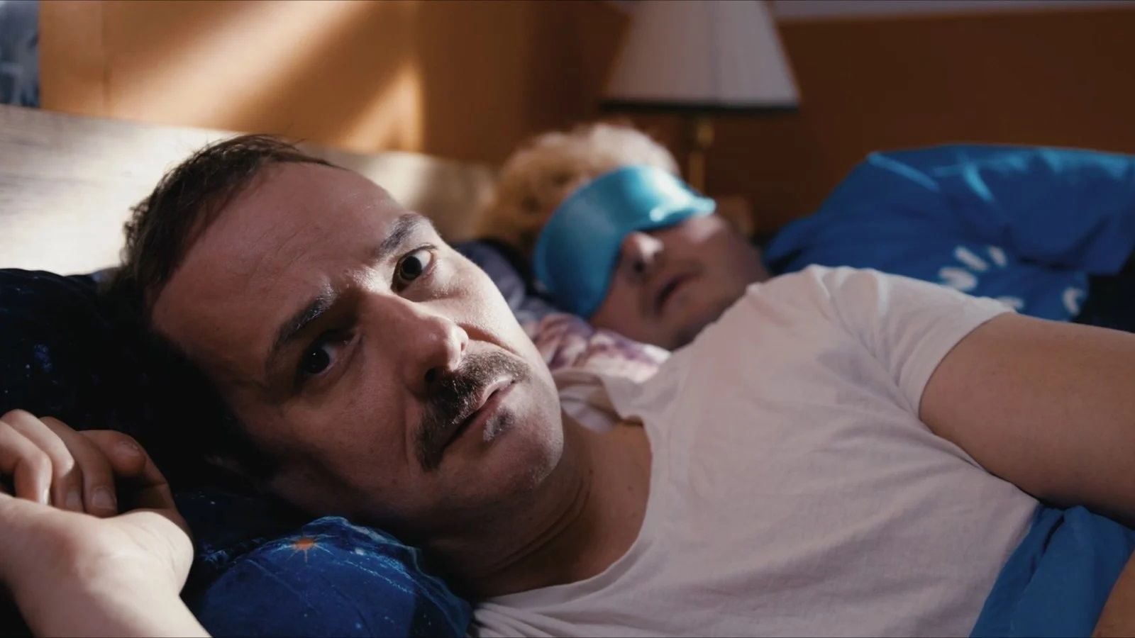 Nachdem die Couch zusammengekracht ist, macht Robert (Andreas Berg) auch im – ziemlich schmalen – Doppelbett seines Gastgebers kein Auge zu.